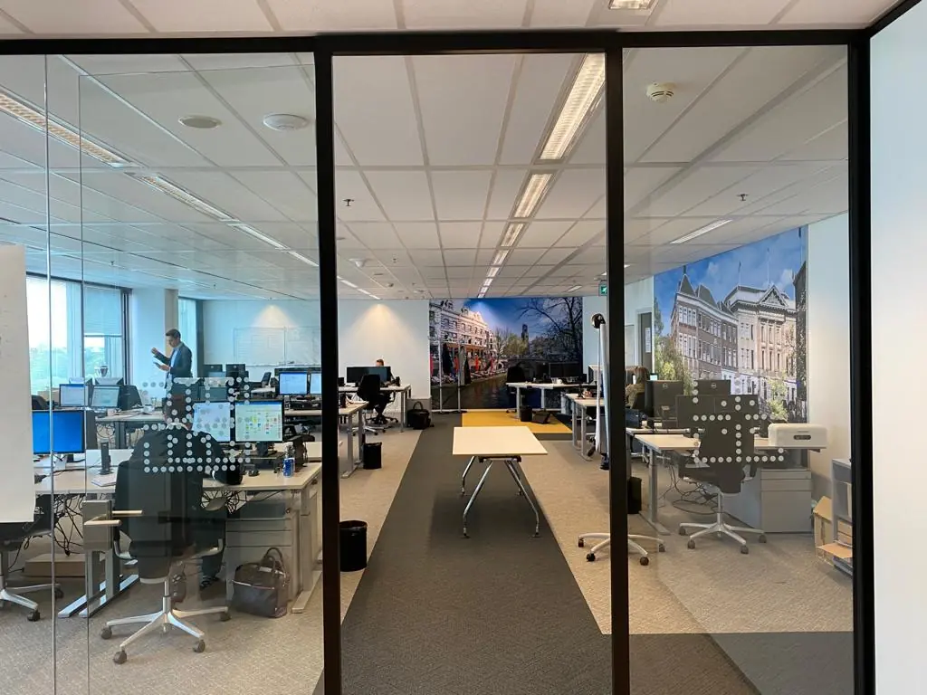 Modern kantoor met werkplekken, computers en een muurdecoratie van een straat aan de Vliegend Hertlaan.